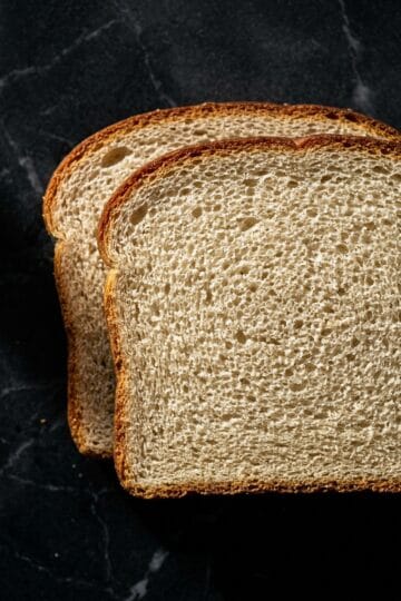 Close-up overhead cross-section of sandwich bread slices showing tight even crumb and golden crust edge